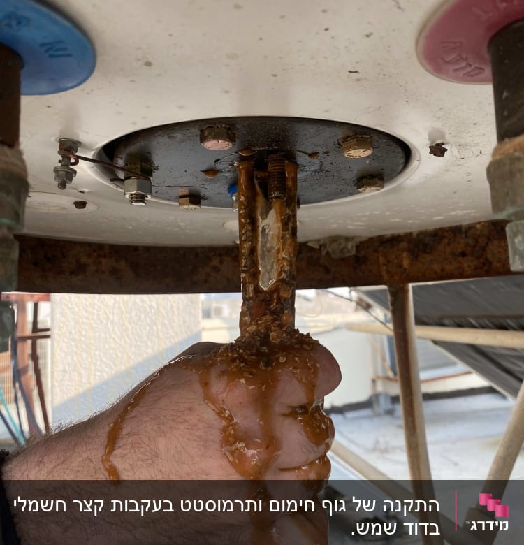 יד אוחזת בצינור דודי שמש עם חלודה ונזילה